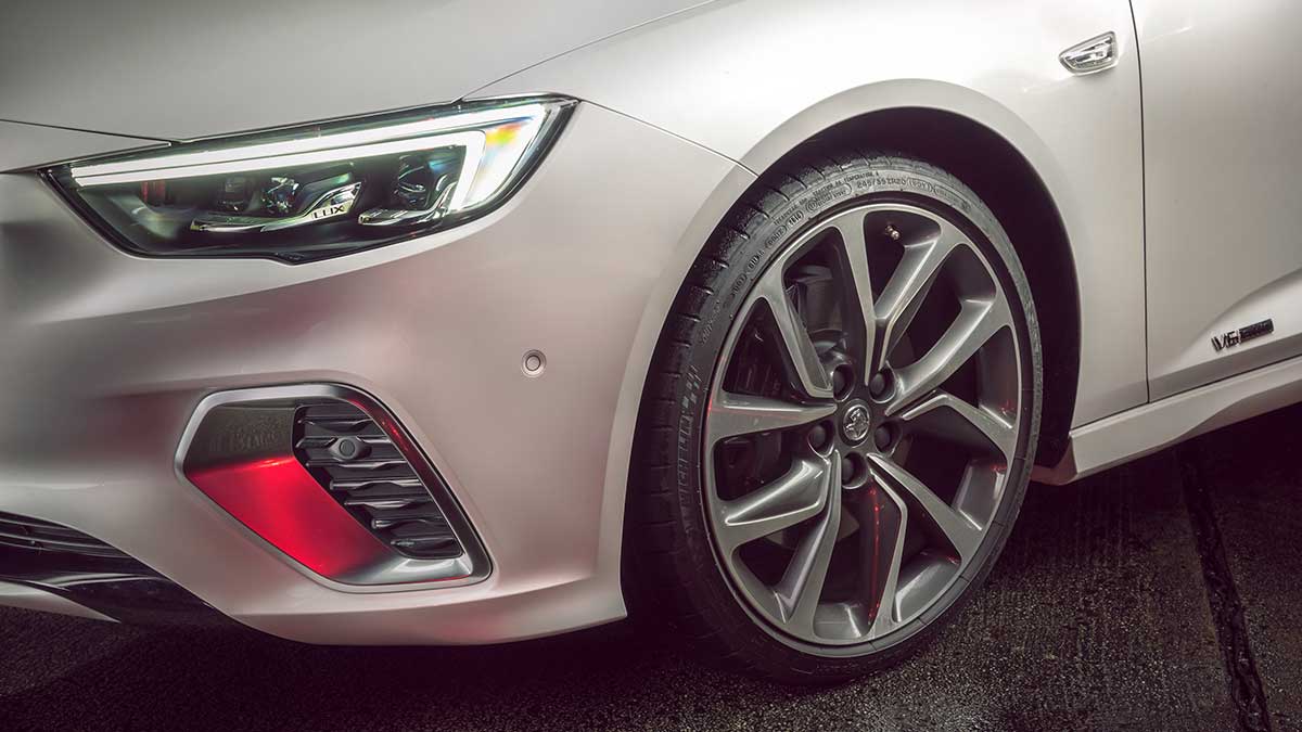 Close up of a parked white Holden ZB Commodore's front wheel and headlights