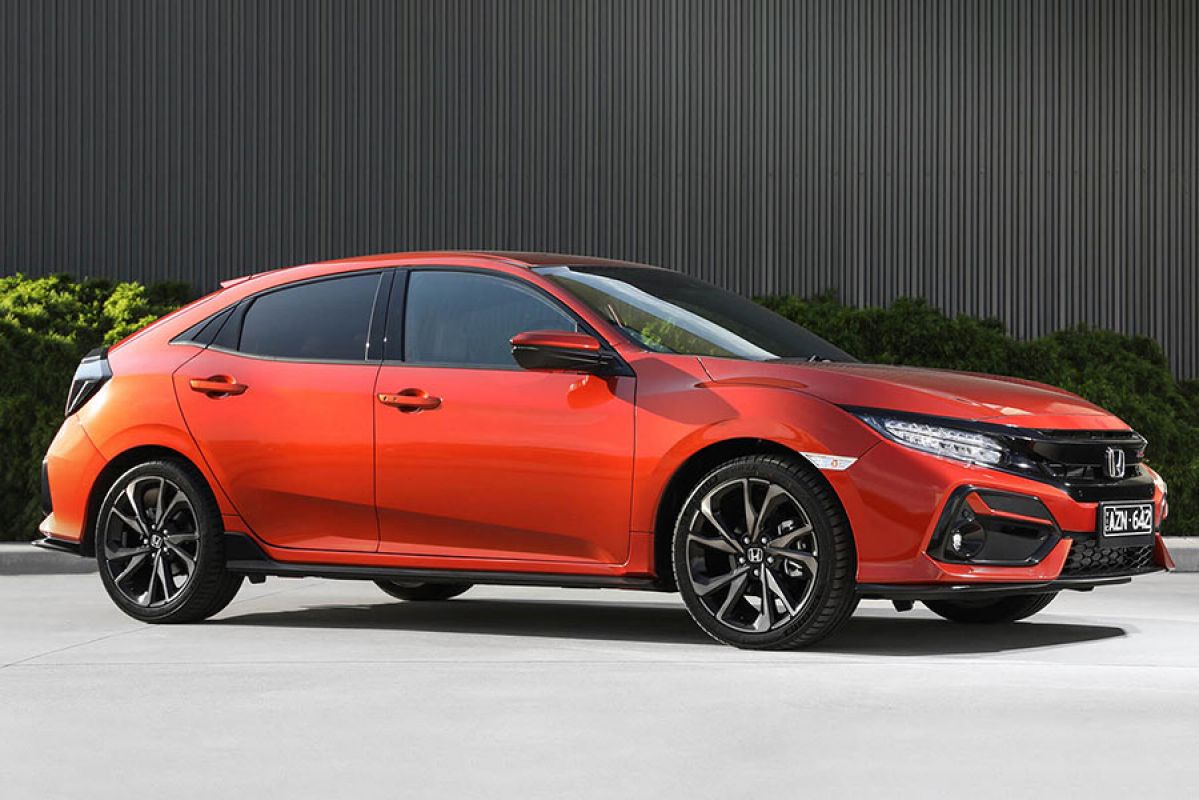 Metallic orange-red Honda Civic RS hatch 2020 car parked on concrete in front of a dark grey corrugated wall