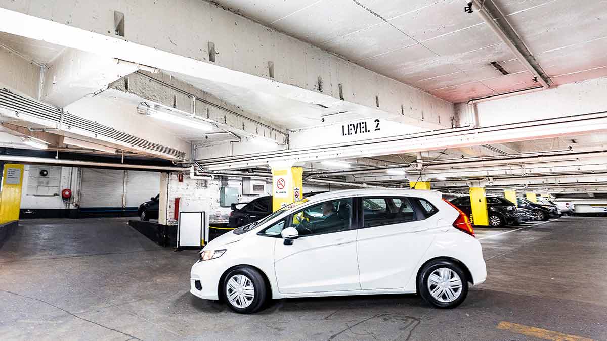 A white Honda Jazz parked in an undercover car park