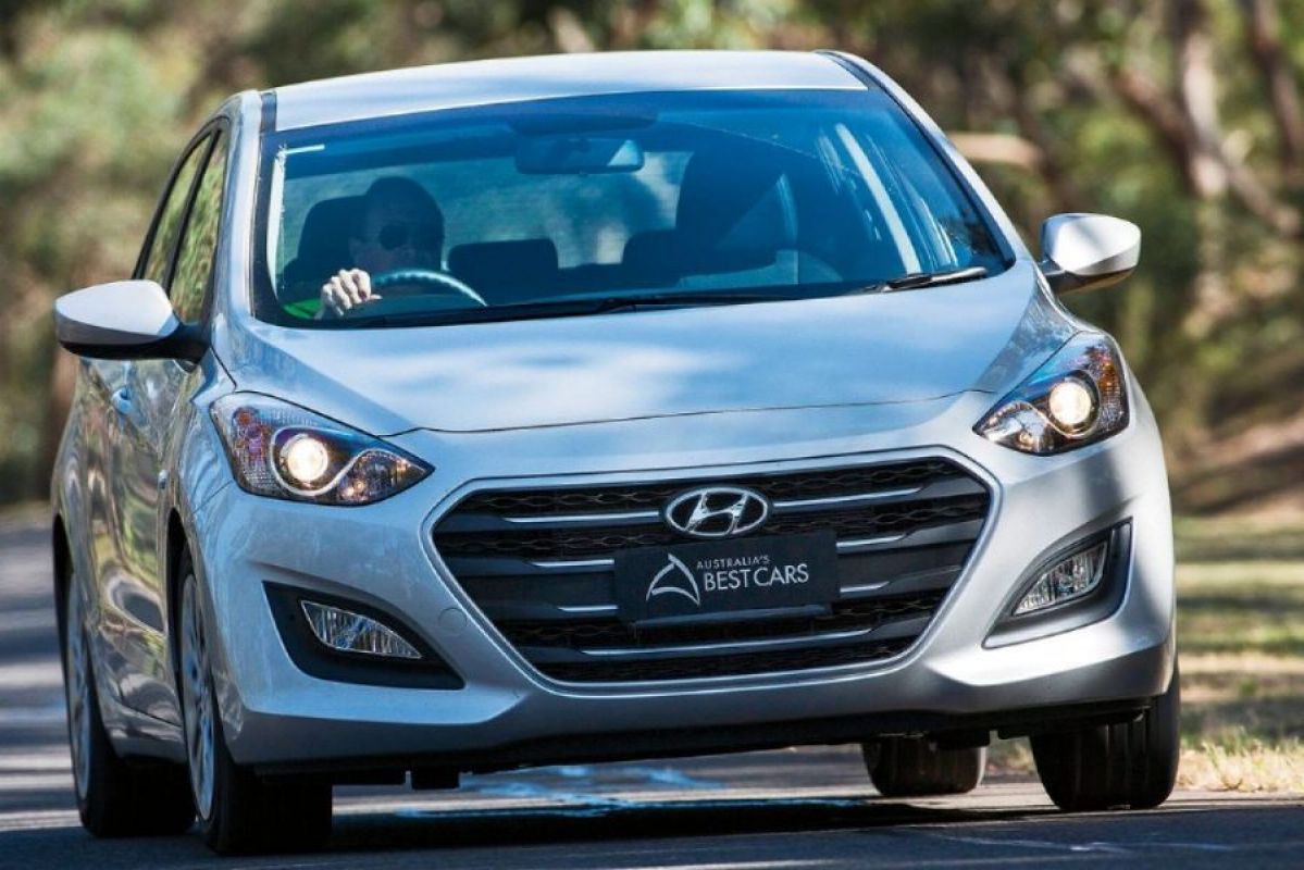 white hyundai active i30 active driving on road surrounded by trees