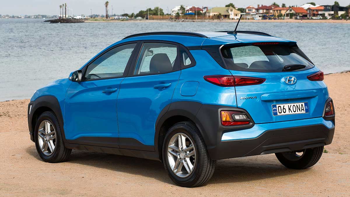 Rear side view of a light blue Hyundai Kona Active parked at the beach