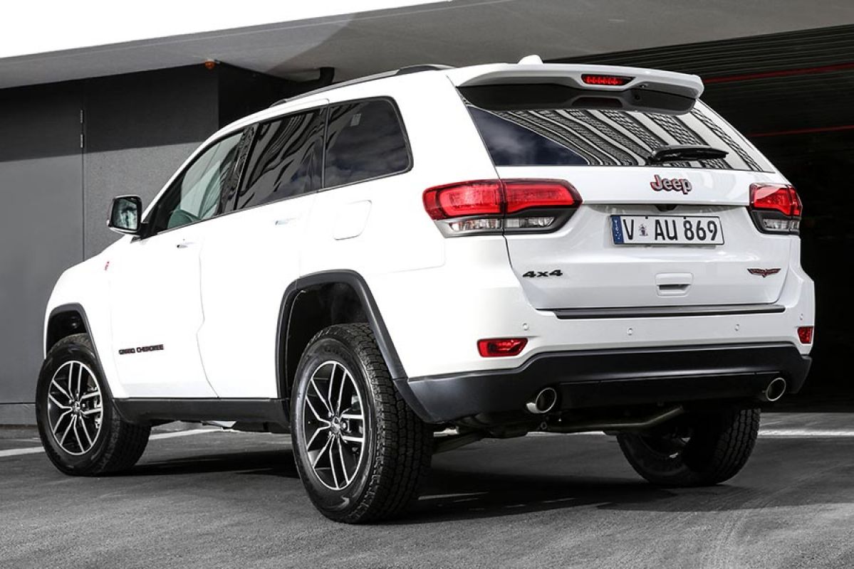 Rear side view of a white Jeep Grand Cherokee Trailhawk 2018 car parked in a driveway