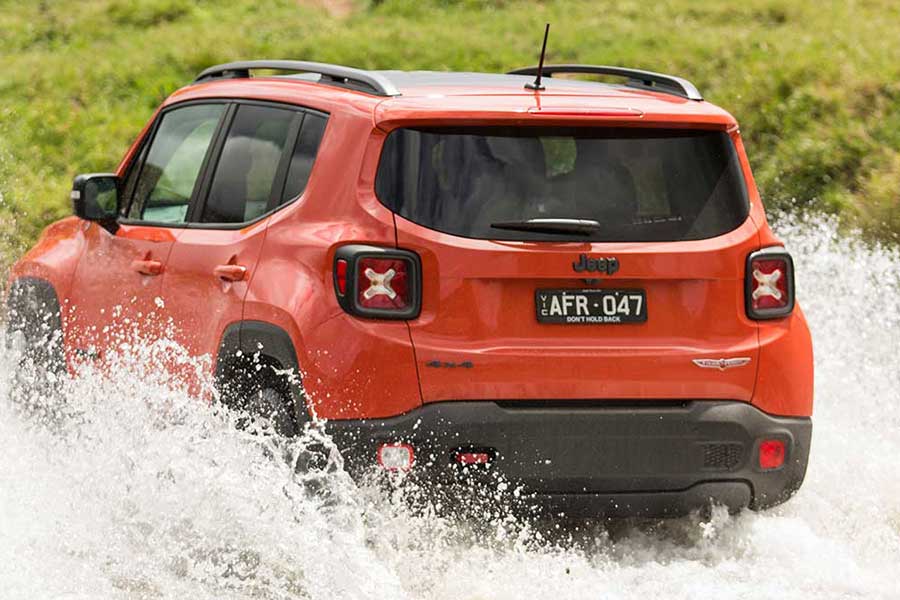 Rear view of Jeep renegade as it drives through a river crossing  