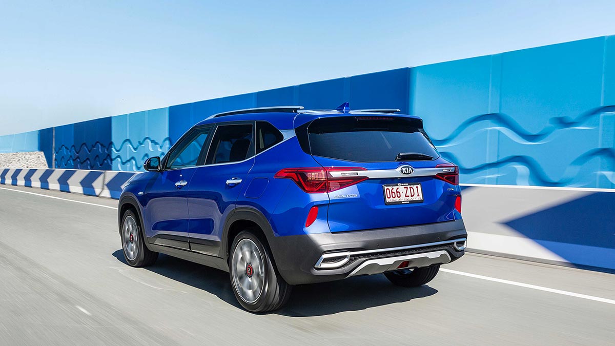 Rear side view of a blue Kia Seltos in motion