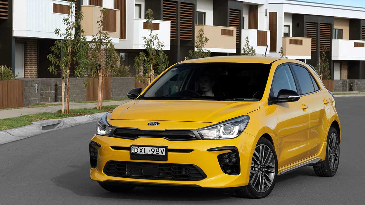 Front side view of a yellow Kia Rio GT-Line parked in front of apartments