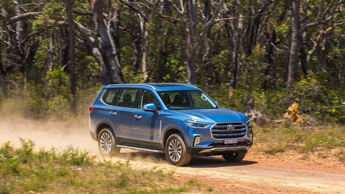 Front side view of a blue LDV D90 driving on a dirt road