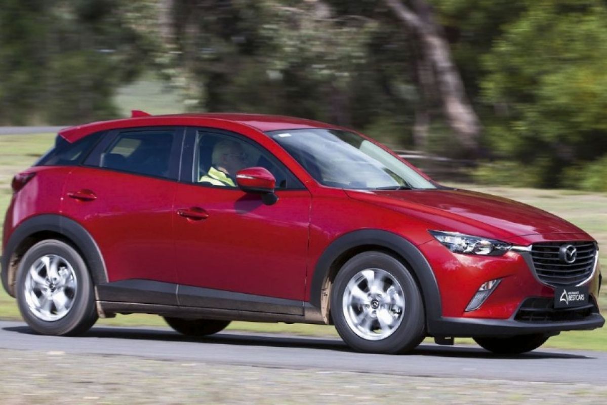 red mazda cx3 driving on road