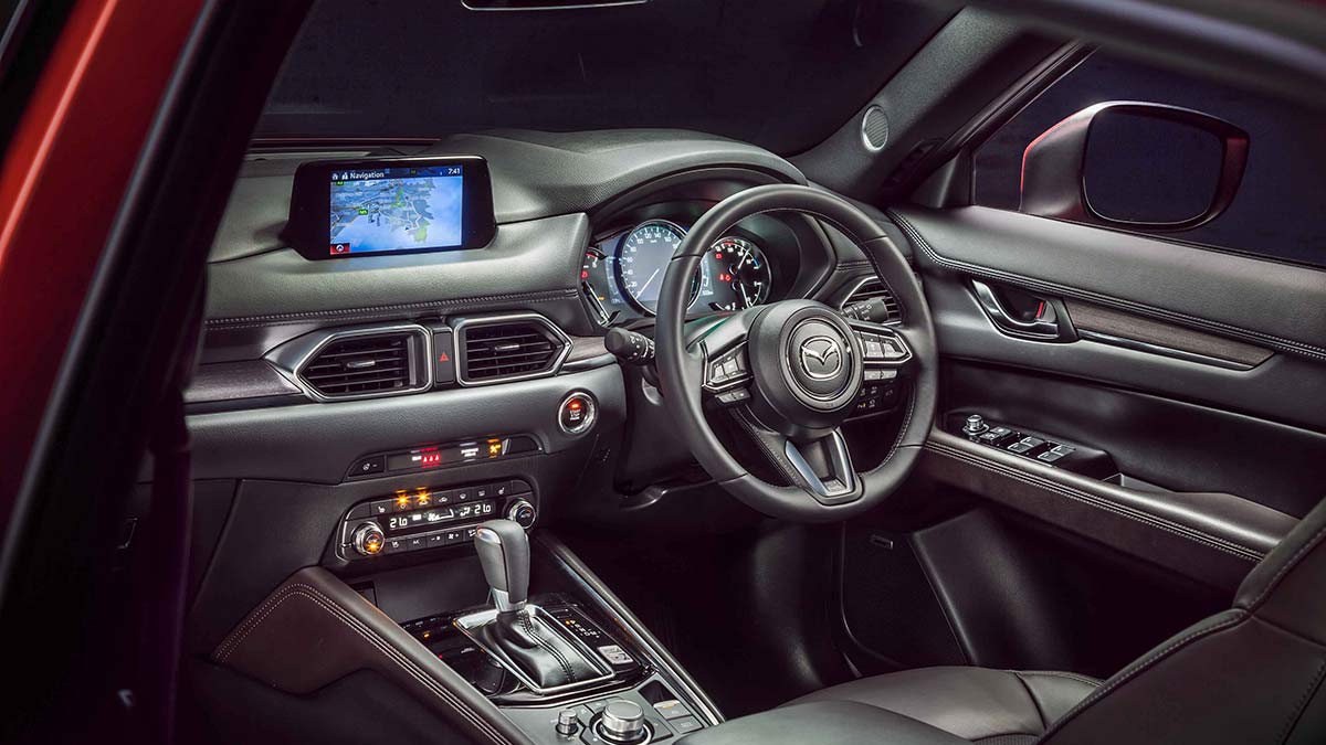 The interior features of a red Mazda CX-5: dash layout, gear stick, and steering wheel