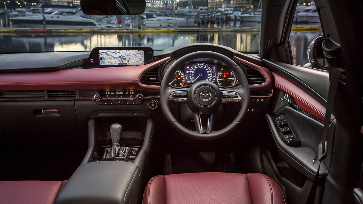 Red and grey interior of the Mazda3 2019 hatch showing the dashboard and steering wheel