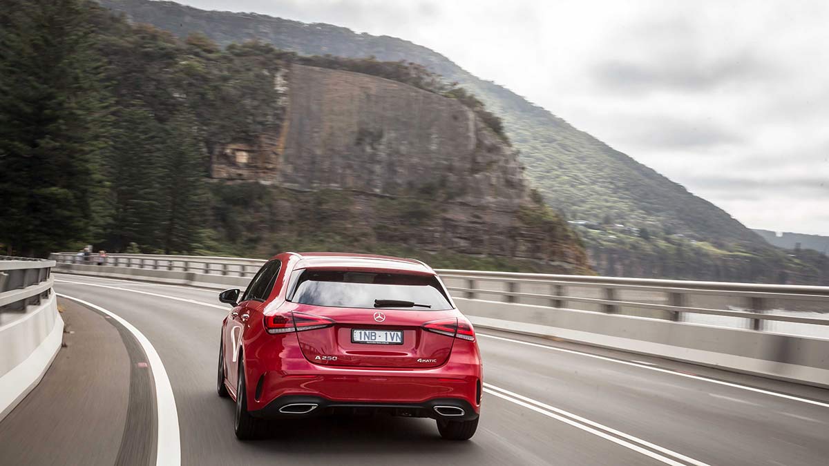 Rear side view of a red Mercedes-Benz A250 4Matic driving on a coastal road