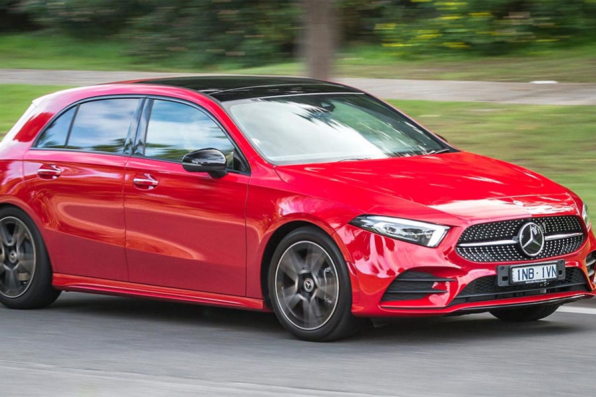 red mercedes benz a250 4matic driving on road next to grass