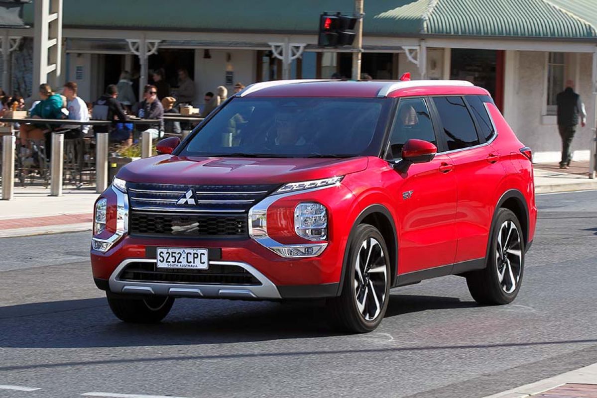 A red Mitsubishi Outlander PHEV on the road.