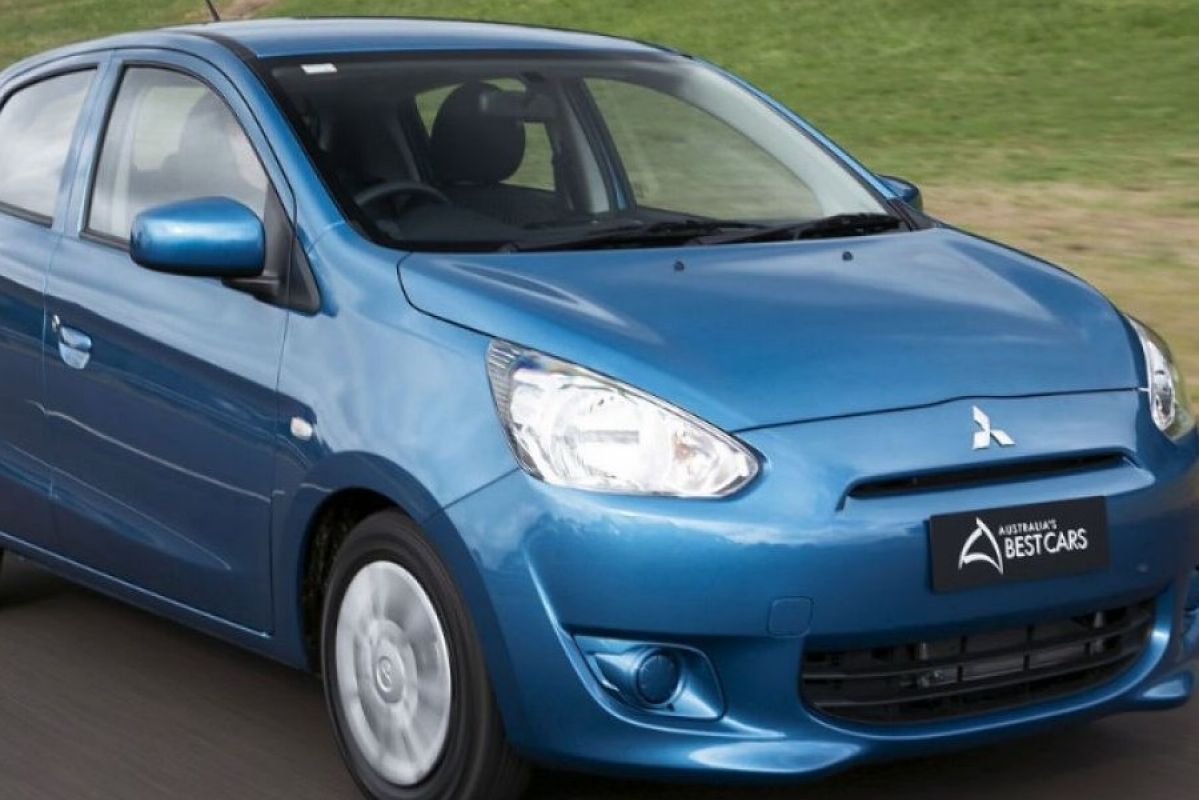 blue mitsubishi mirage driving on road next to grass