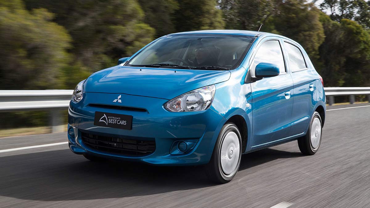 Front side view of a blue Mitsubishi Mirage in motion