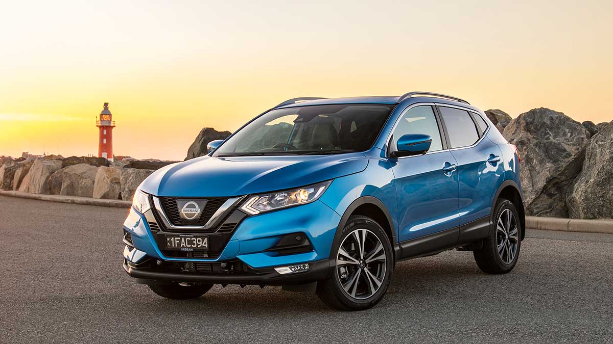 Front side view of a blue Nissan Qashqai parked near a lighthouse at sunset