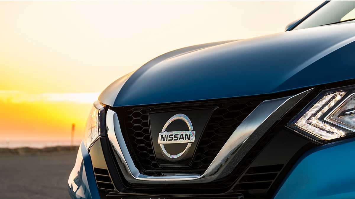 Nissan's emblem on the nose of blue Nissan Qashqai at sunset