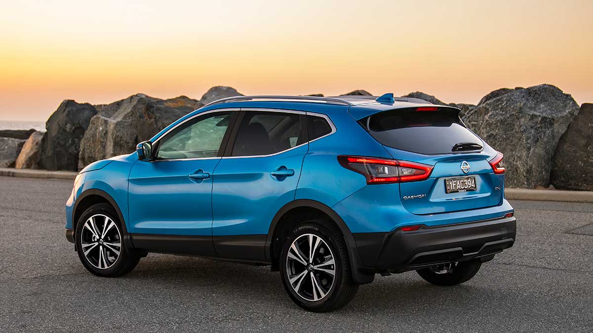 Rear side view of a parked blue Nissan Qashqai facing the sunset