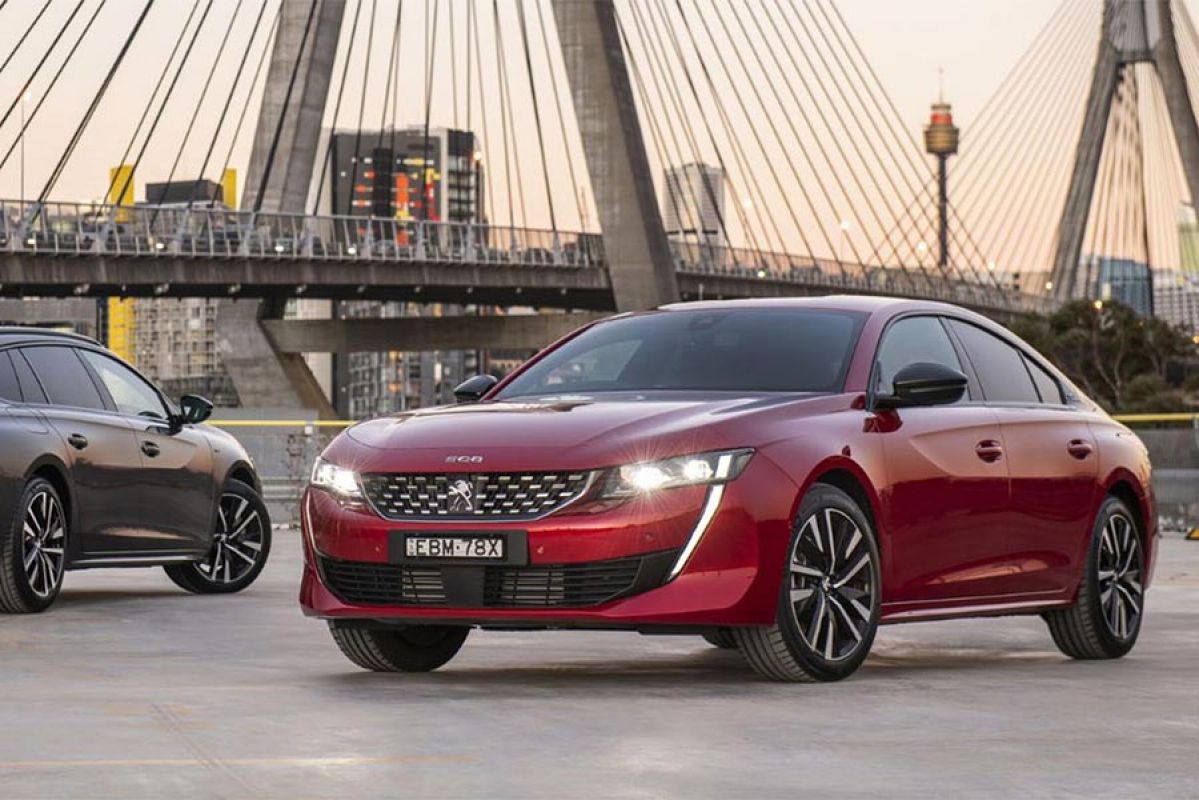 Red Peugeot 508 GT 2019 parked infront of bridge 