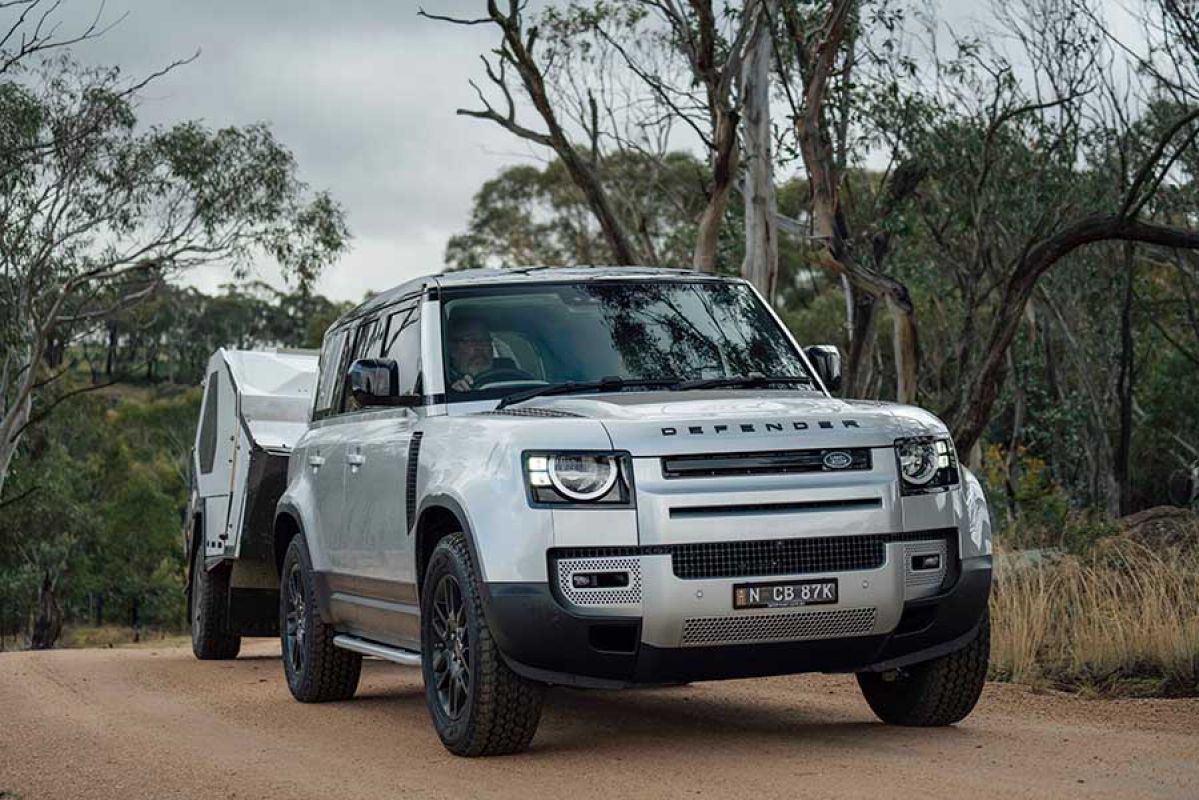 Silver Land Rover Defender driving through mud