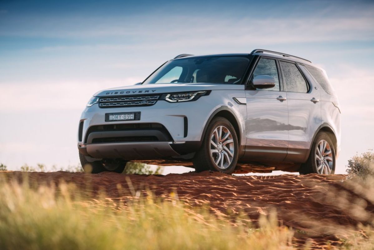 white land rover discovery parked on top of grassy hill