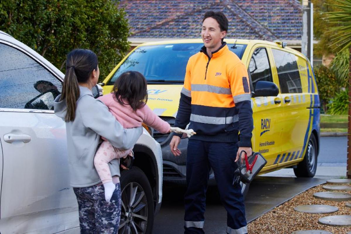 RACV roadside assistance man walking towards broken down car with woman and child