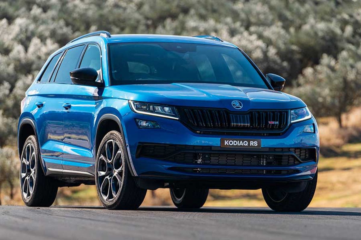 Front and side view of a blue Skoda Kodiaq RS driving on a road 