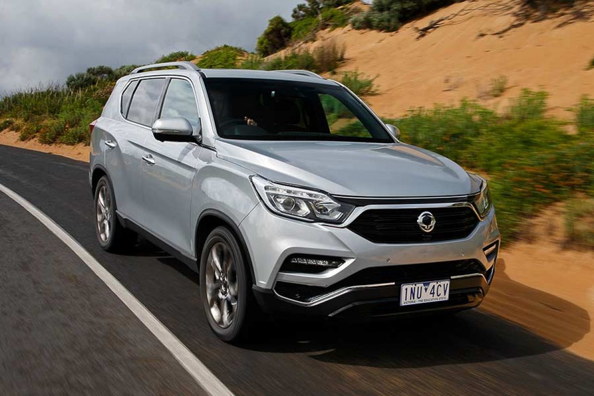 Front and side view of silver SsangYong Rexton driving on road 