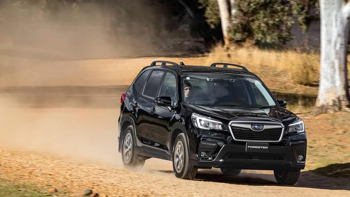 Front side view of a black Subaru Forester driving on a dusty, dirt road