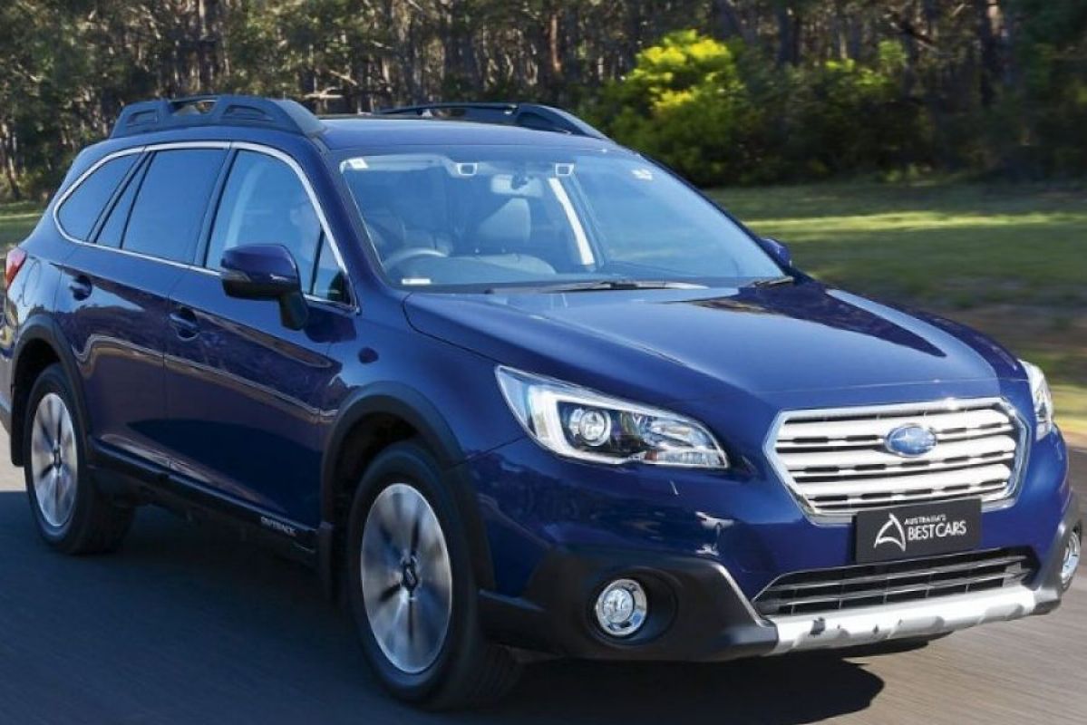 blue subaru outback premium driving on road next to grass and tress