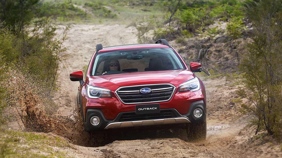  A red Subaru Outback driving through a muddy dirt road