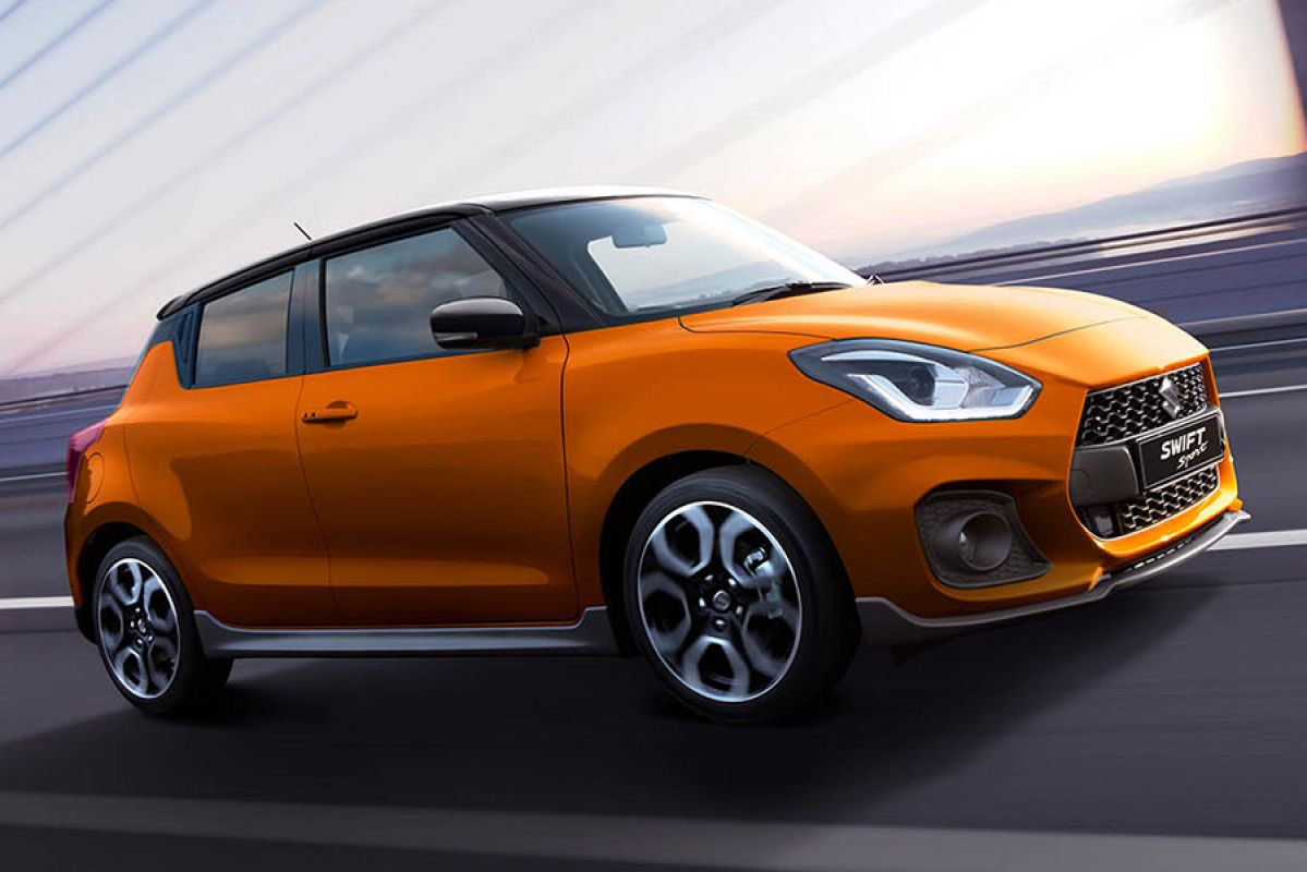 Side front view of a bright orange Suzuki Swift Sport 2020 in motion on a freeway