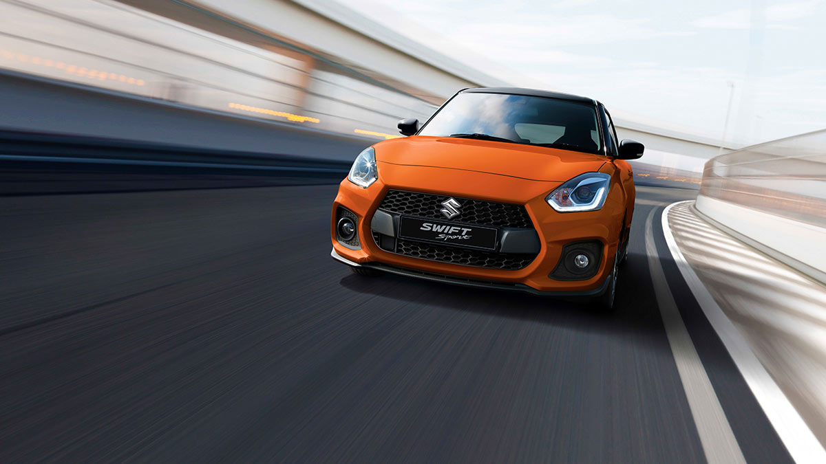 Front view of a bright orange Suzuki Swift Sport 2020 in motion