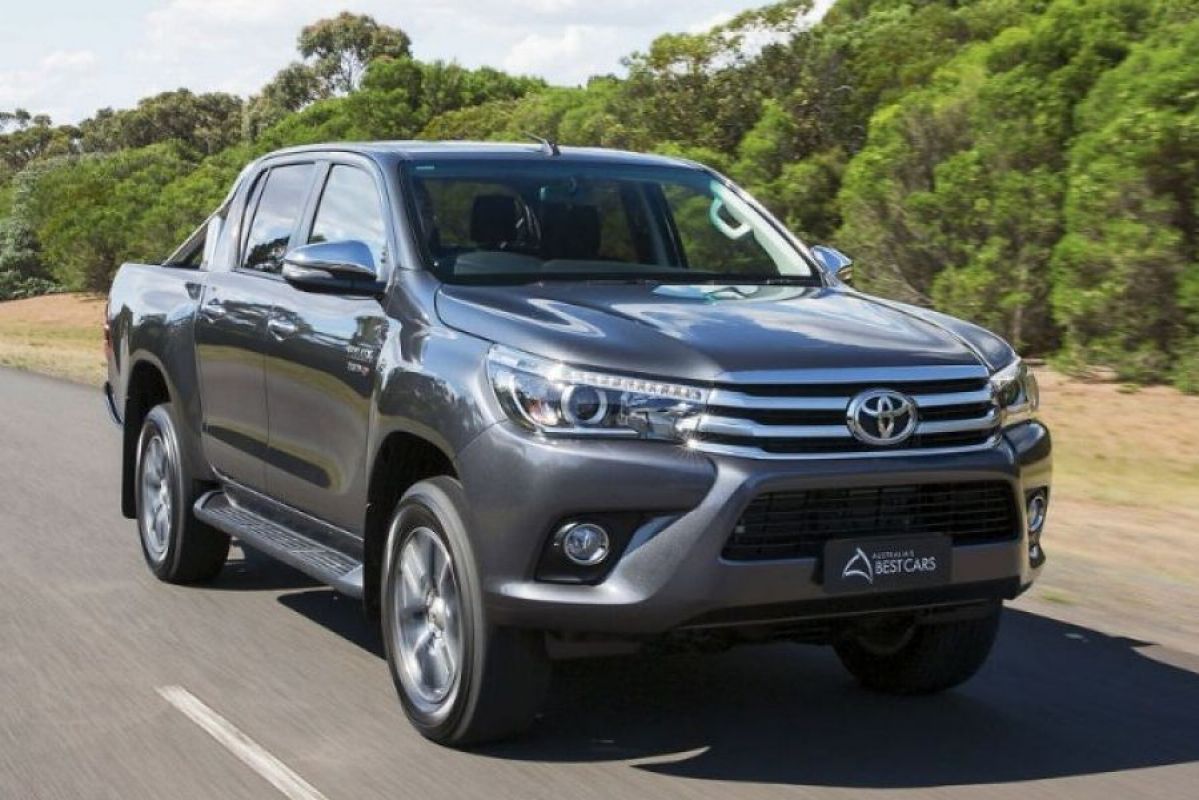 grey toyota hilux driving on country road next to bushes