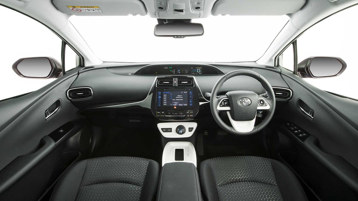 Dark grey interior of the Toyota Prius showing the front seats, dashboard, centre console and steering wheel