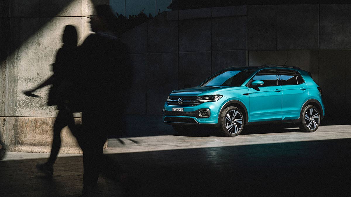 Front side view of a turquoise Volkswagen T-Cross 85 TSI Style 2020 parked under a concrete structure