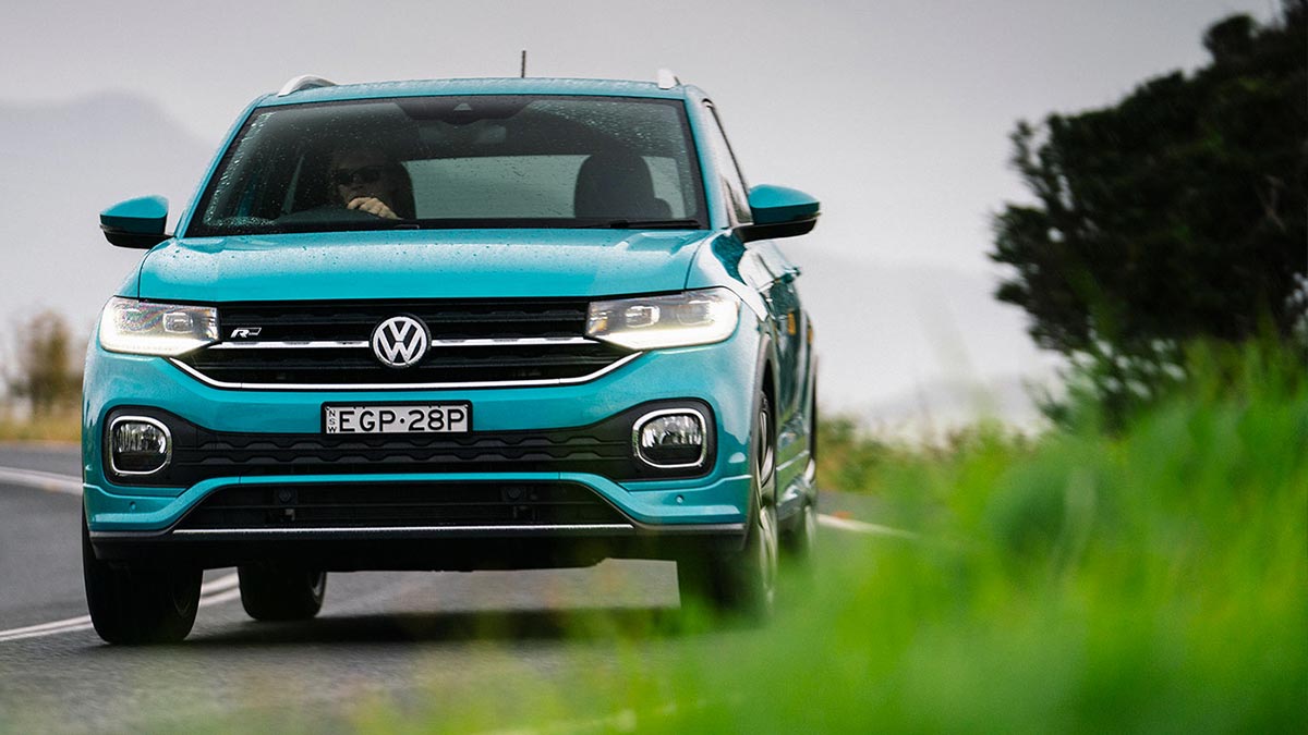 Front view of a turquoise Volkswagen T-Cross 85 TSI Style 2020 car in motion on a road