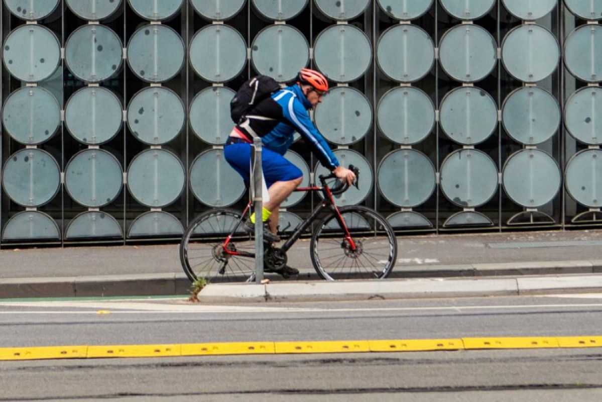 A cyclist wearing a helmet cycling past the RMIT Design Hub in Melbourne