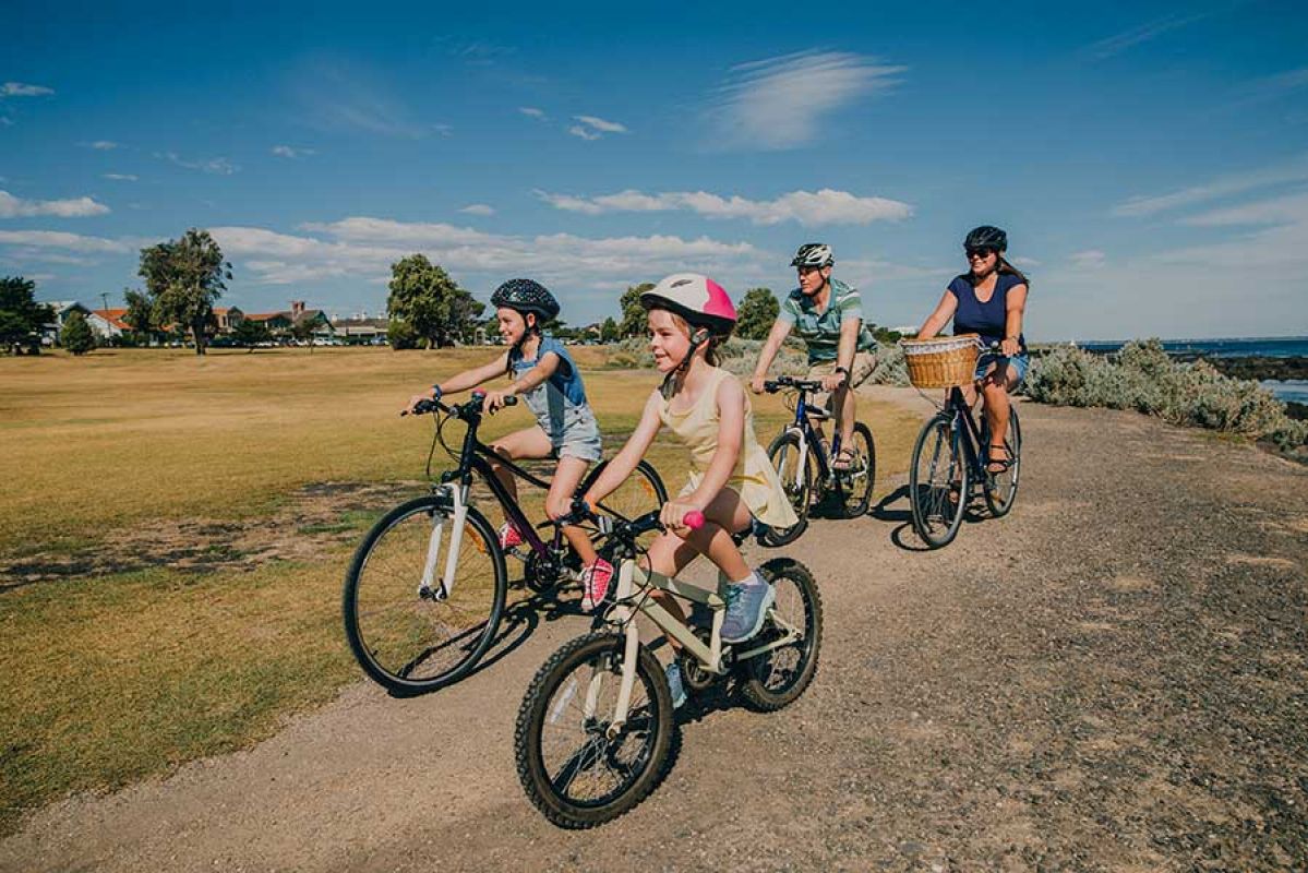 Family of four riding bikes in a park