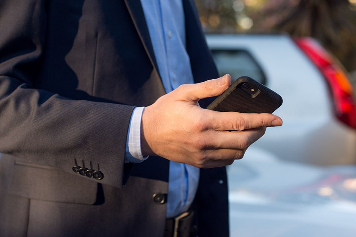 woman with smartphone on street with parked cars