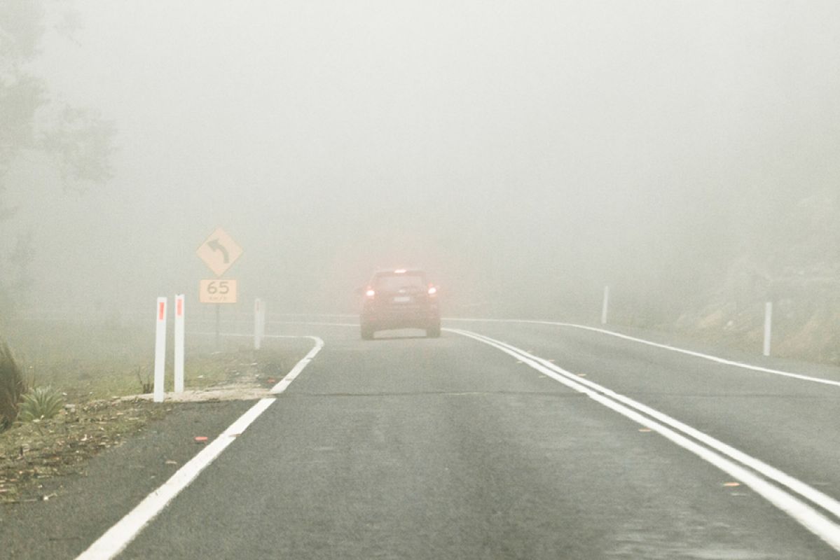 A car driving in thick fog on a country road