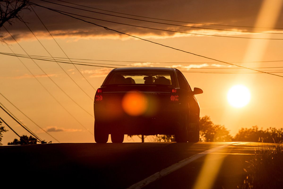 Cars driving on road on hot day at sunset