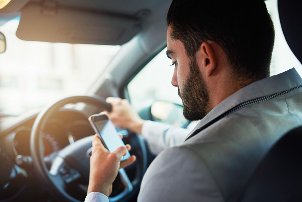 A man holding a mobile phone while driving.