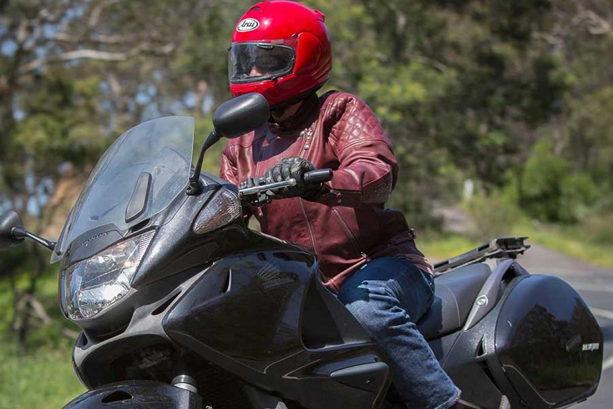 Motorbike rider with red helmet riding on road.