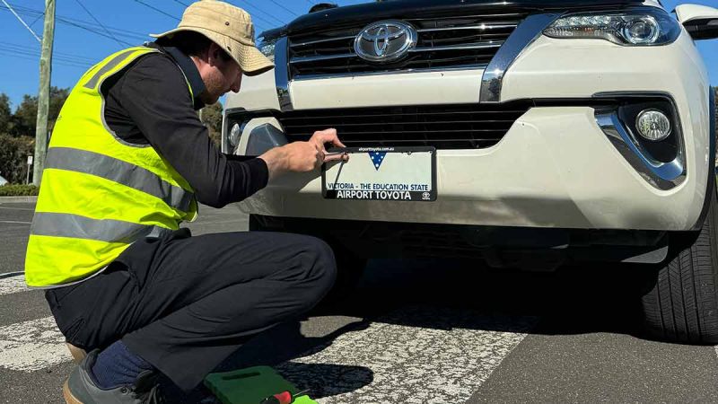 man screwing on car number plate