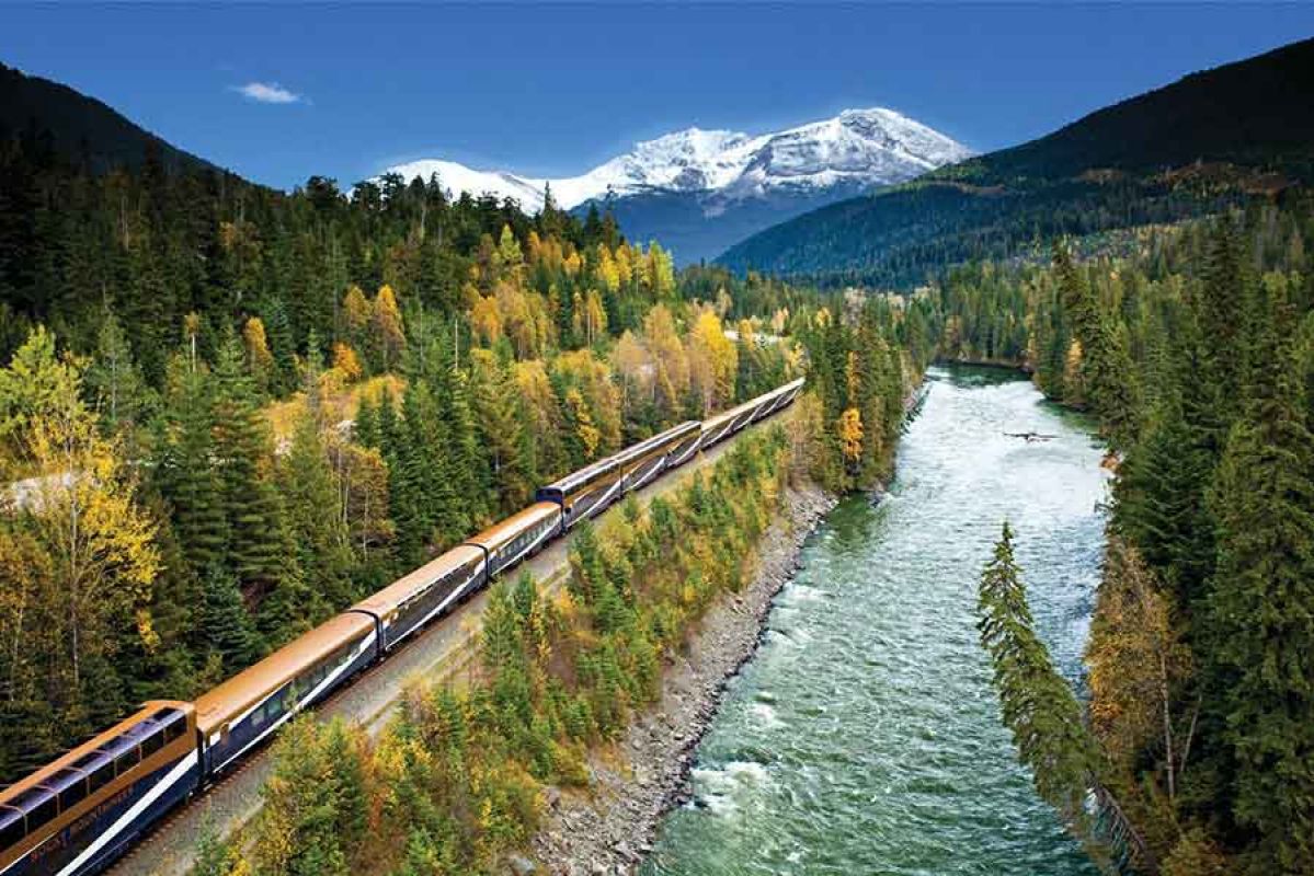 mountains in Canada surrounded by lakes with train rolling through 