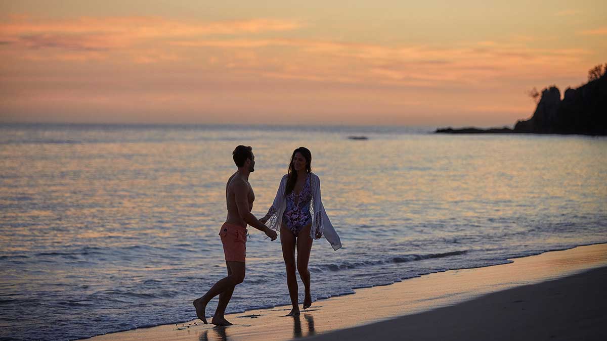 couple holding hands on beach at sunset