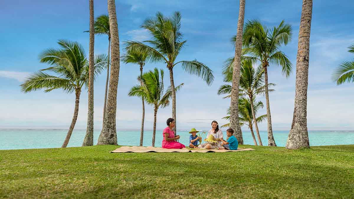 four people sitting on picnic rugs on tropical island 