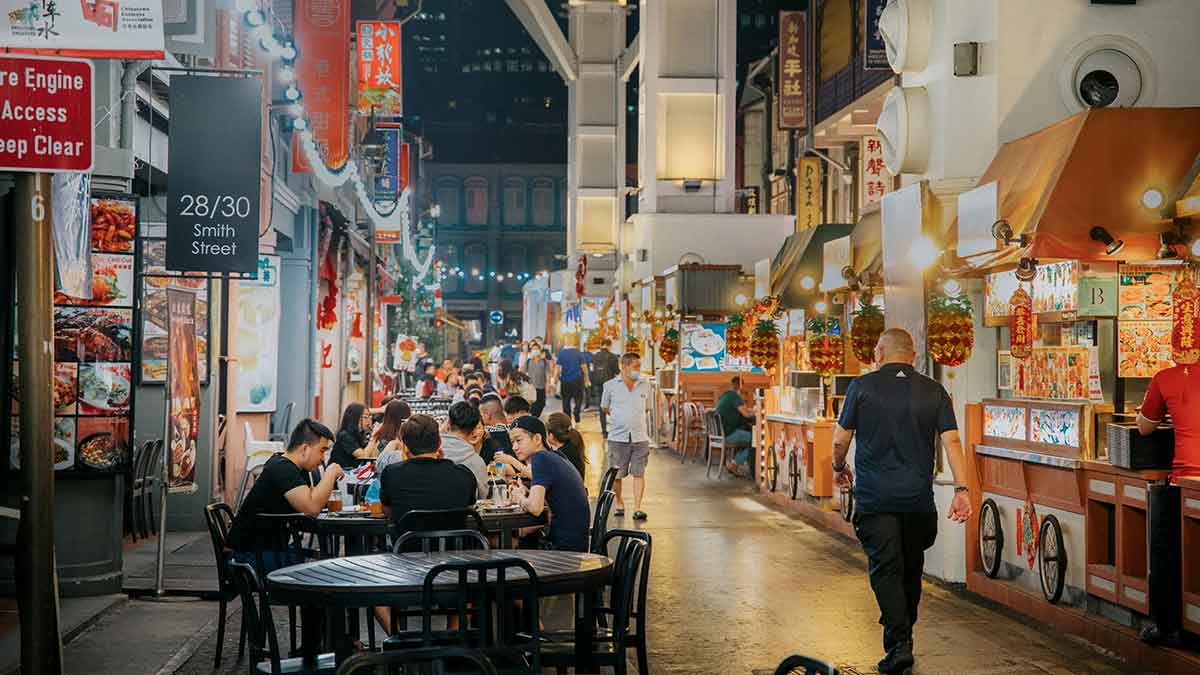 people sitting at tables eating street food