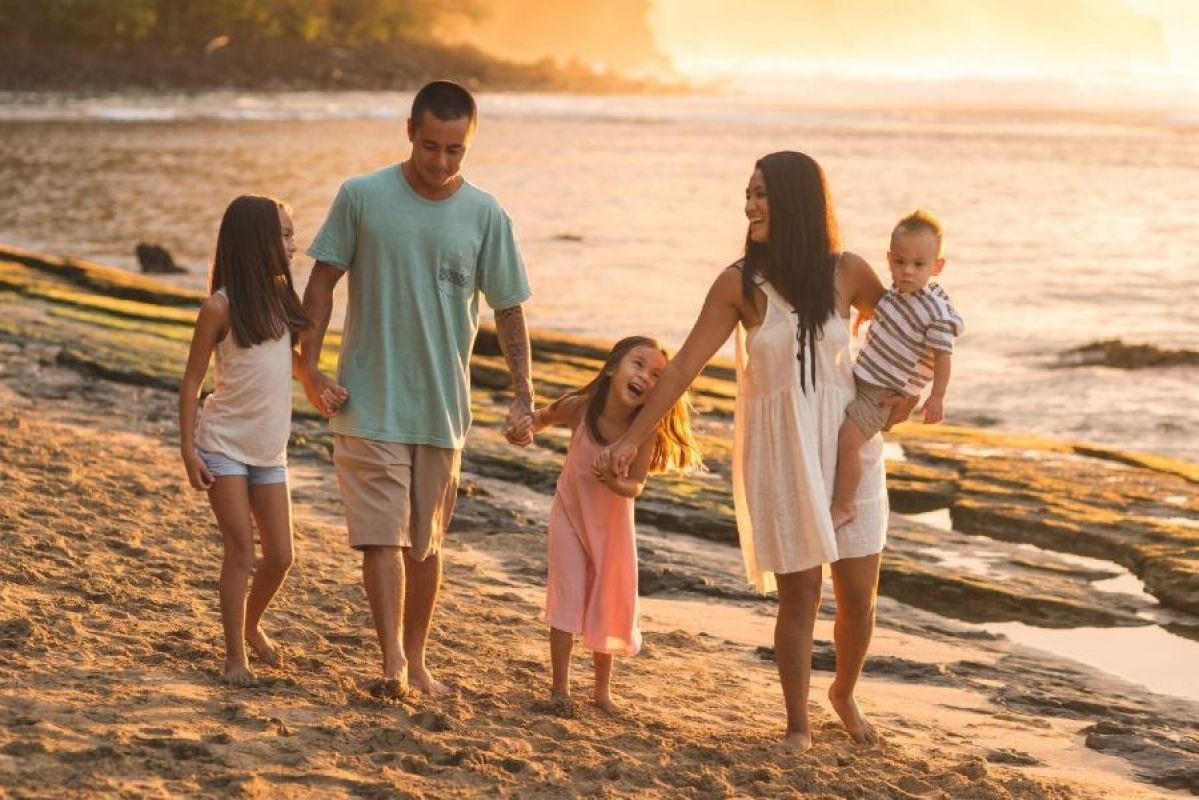 a young family walking along a beach in Hawaii