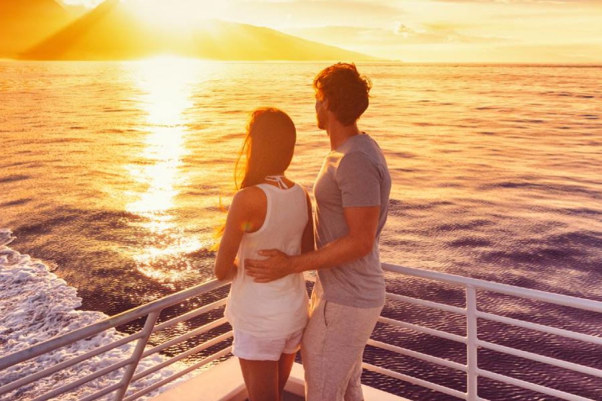 man and woman watching the Hawaiian sunset from a boat